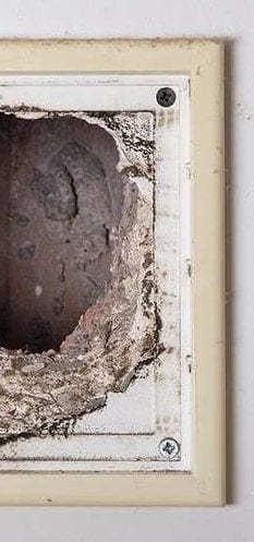 A dirty air duct vent opening clogged with dust
