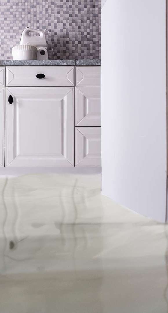 A white kitchen with water flooding the tiled floor