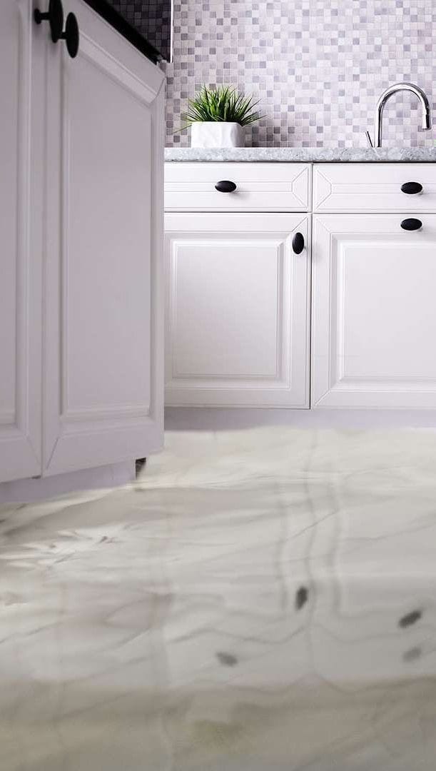 Water spreading across the tiled floor of a white kitchen